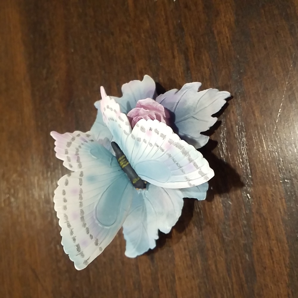 Lovely resin collectible of butterfly on a curly leaf in blues and pink.